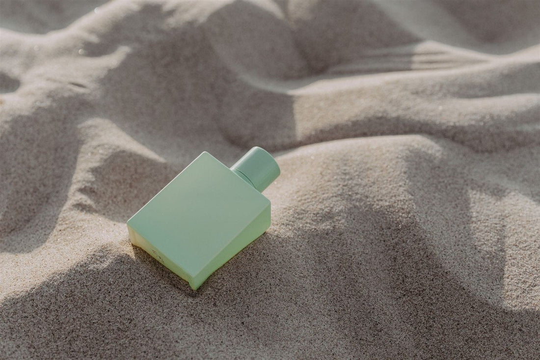 Frasco de perfume verde sobre arena